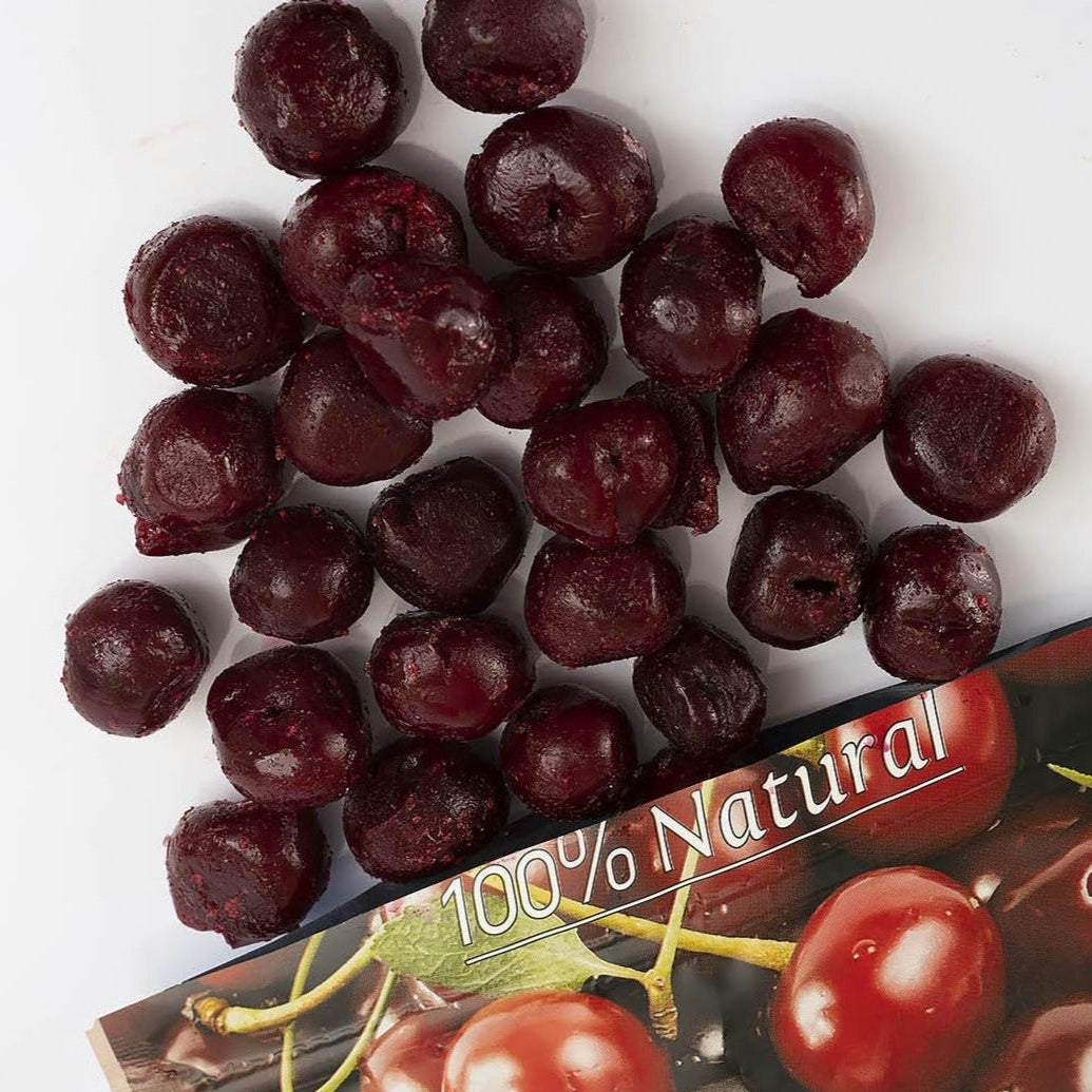 A package of Cherarium Gardenia cherries with several dark red cherries scattered on top, photographed on a clean white background. The box shows a glossy cherry illustration and the text '100% Natural'.